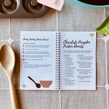 Load image into Gallery viewer, &quot;Yum! Protein-Packed Smoothies &amp; Snacks for Chocolate Lovers&quot; Cookbook, open to page 34, on a surface with a tablecloth, mixing spoons, and other baking tools